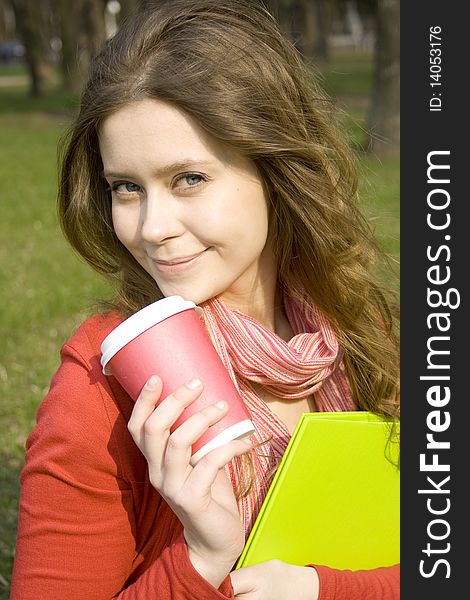 Young beautiful student at a dinner in the park drinking coffee. Keep folder. Young beautiful student at a dinner in the park drinking coffee. Keep folder