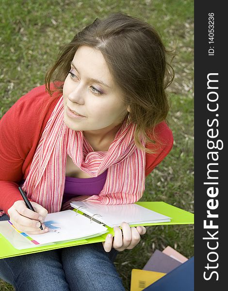 Young beautiful woman sitting on the grass in the park and draws sketches. Student. Young beautiful woman sitting on the grass in the park and draws sketches. Student