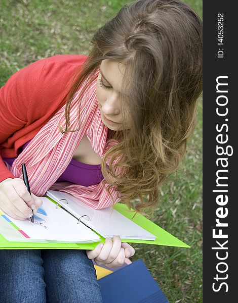 Young beautiful woman sitting on the grass in the park and draws sketches. Student. Young beautiful woman sitting on the grass in the park and draws sketches. Student