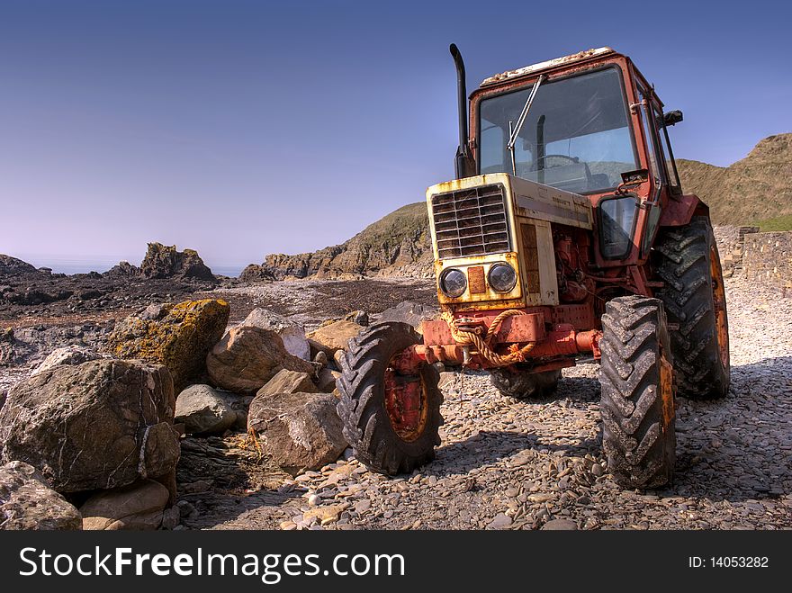 Frontside of Old, rusty tractor on a pebble beach