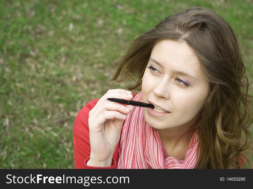 Young woman sunny day in the park thought. Biting pen. Young woman sunny day in the park thought. Biting pen