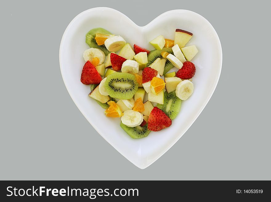 Five fresh fruits in a fruit salad in heart shaped dish. Five fresh fruits in a fruit salad in heart shaped dish