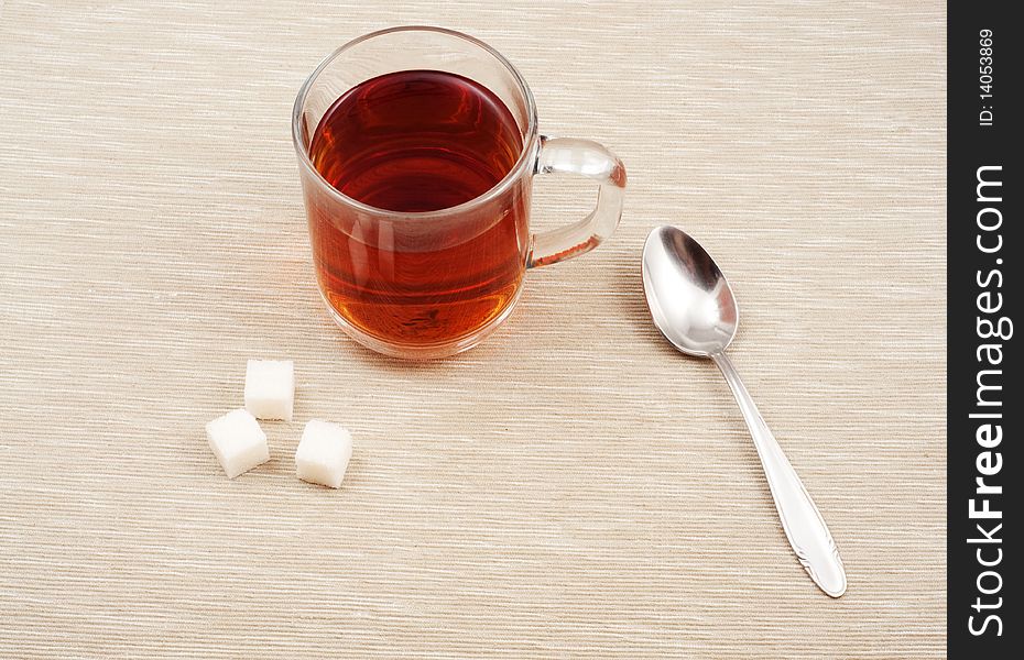 Glass cup of tea with spoon and sugar