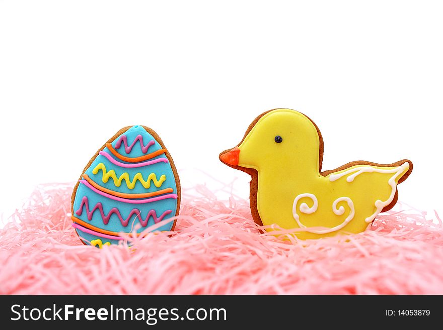 Close up of easter egg and duck cookies on pink ribbons over white background. Close up of easter egg and duck cookies on pink ribbons over white background.