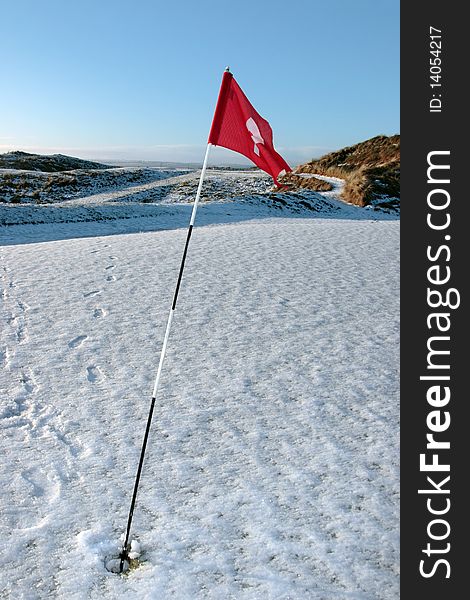 Snow covered links golf course flag