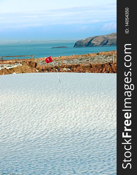 Snow covering on a golf course in ireland in winter with sea and cliffs in background. Snow covering on a golf course in ireland in winter with sea and cliffs in background