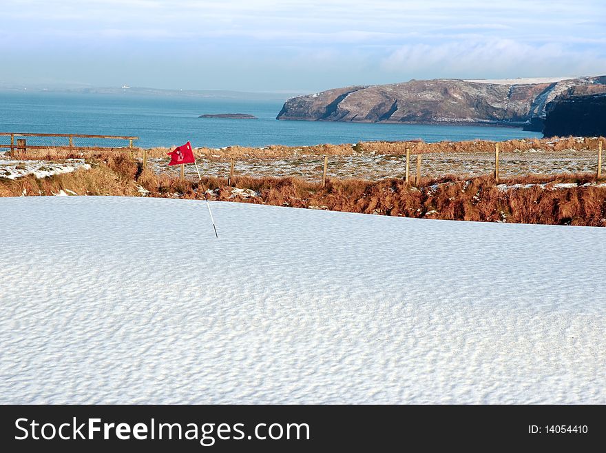 Snow covering on a golf course in ireland in winter with sea and cliffs in background. Snow covering on a golf course in ireland in winter with sea and cliffs in background