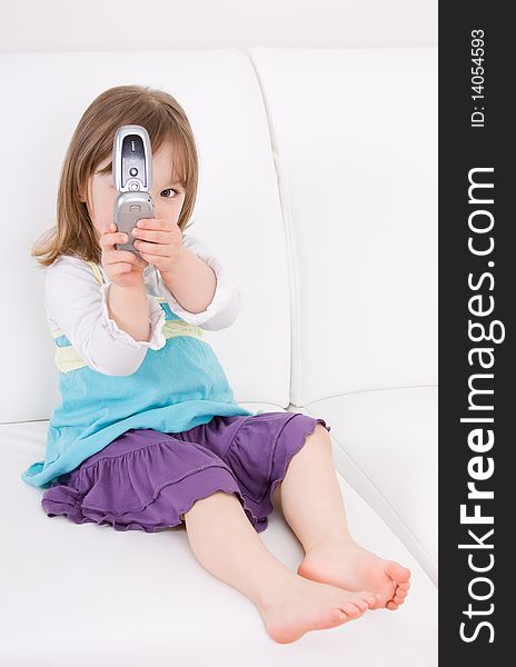 Little girl with mobile phone on sofa