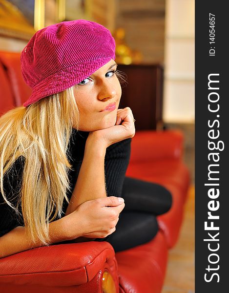 Young funny casual blond woman on red sofa