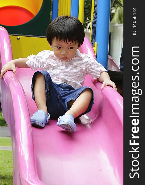 An Asian boy playing on a slide. An Asian boy playing on a slide