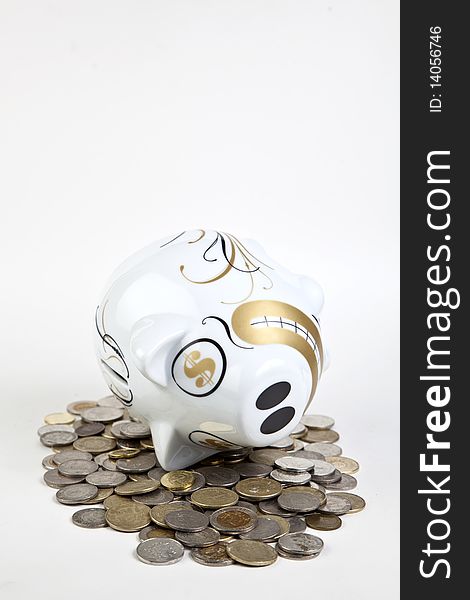 Money spilled out of a piggy bank, fallen on it's side, is spread out over the table. Money spilled out of a piggy bank, fallen on it's side, is spread out over the table