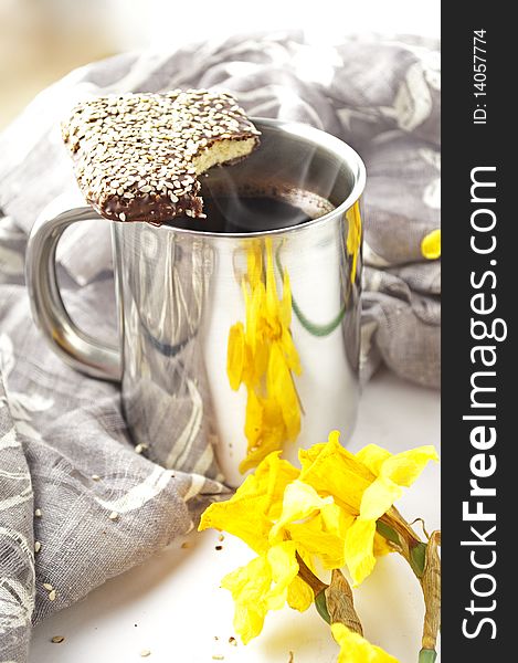 A cup of coffee with chocolate cake in sesame. Daffodils.