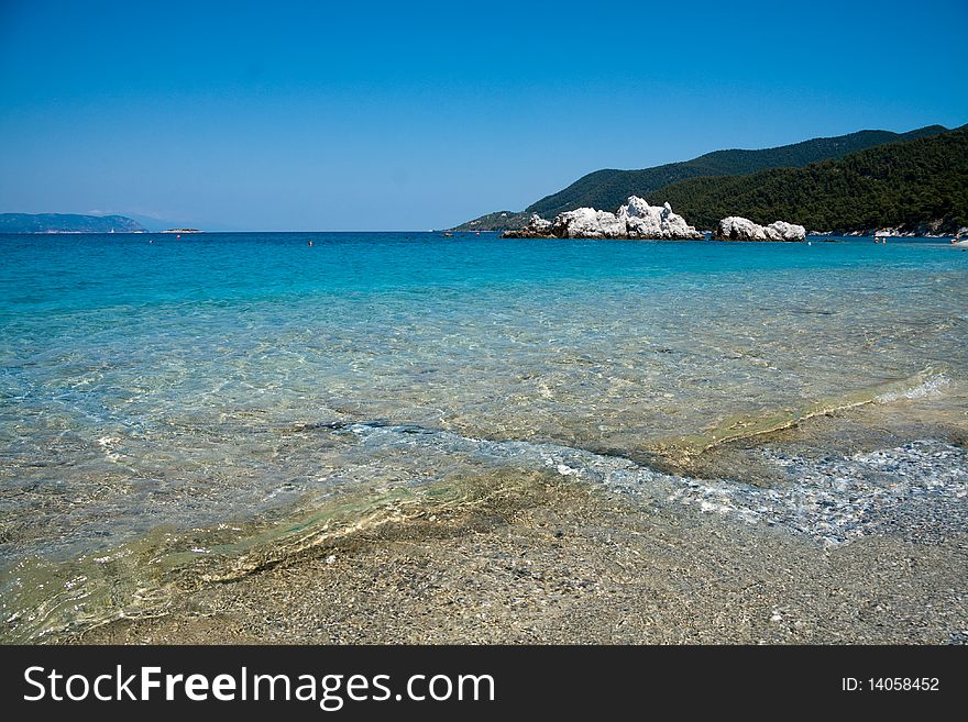 Calm blue Mediterranean beach with bleached white rocks in the distance. Calm blue Mediterranean beach with bleached white rocks in the distance