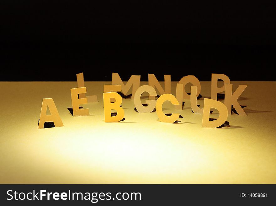 Letters cutting from yellow paper standing on dark background. Letters cutting from yellow paper standing on dark background
