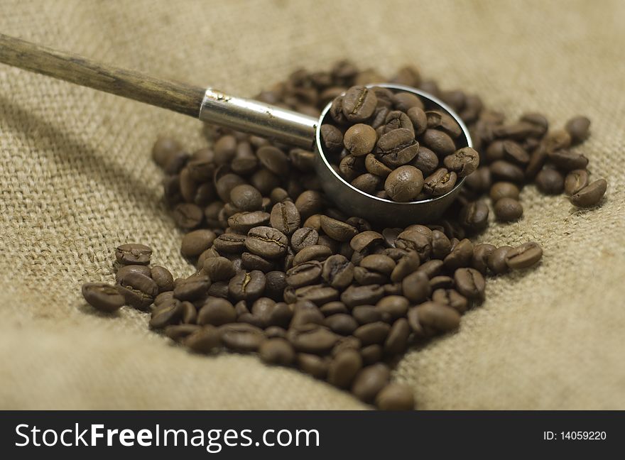 Coffee beans with a scoop on linen bag, close up