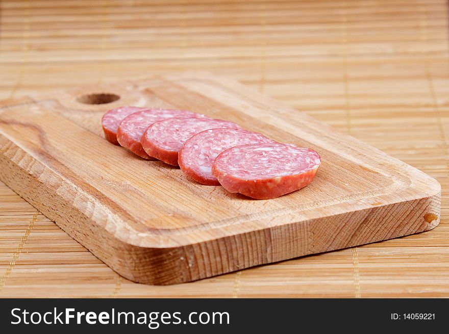 Many piece of sausage on brown kitchen board