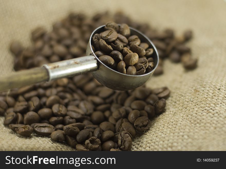 Coffee beans in a scoop, close up, linen background. Coffee beans in a scoop, close up, linen background