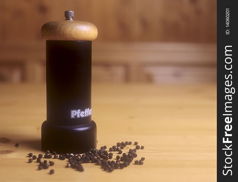 A pepper mill and peppercorn on a desk top