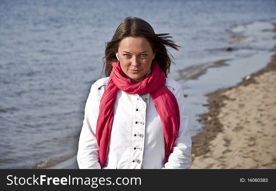 A beautiful young girl walking on the beach in spring. She looks into the camera with green eyes.
