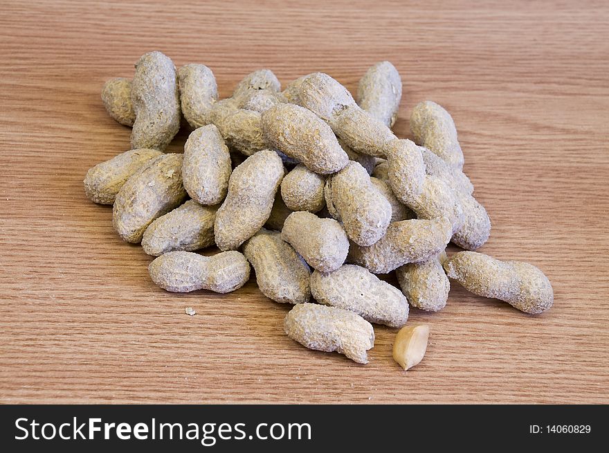 Whole salted peanuts, on light wood background