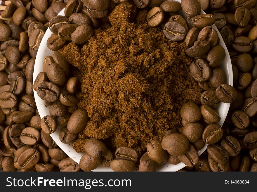 Coffee beans and ground coffee, mixed together and being shoot from  above.