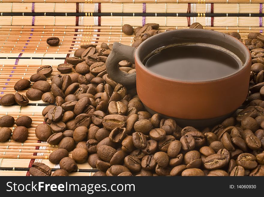 A cup wirh coffee surrounded by coffee beans