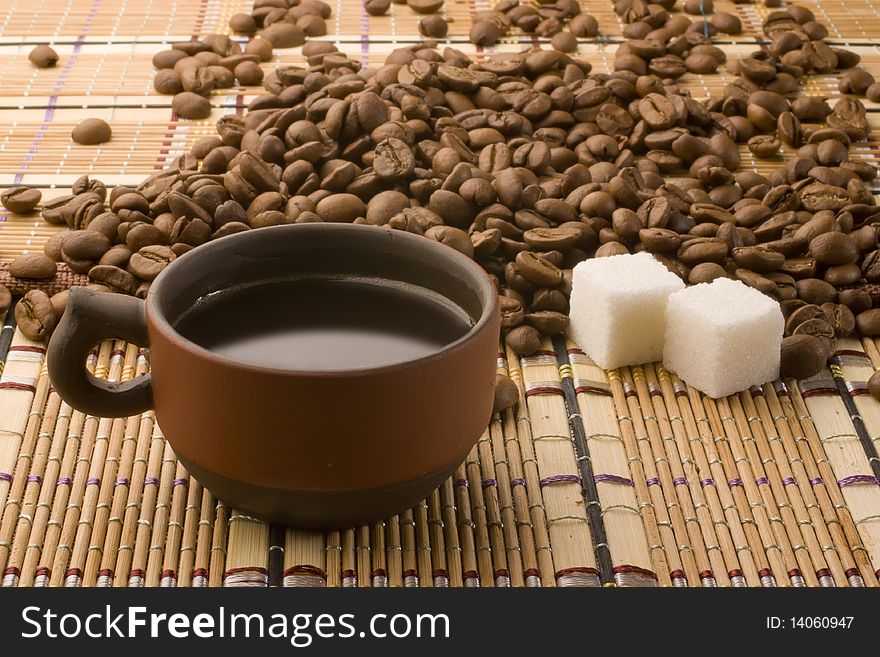 A cup of coffee and sugar cubes surrounded by coffee beans. A cup of coffee and sugar cubes surrounded by coffee beans