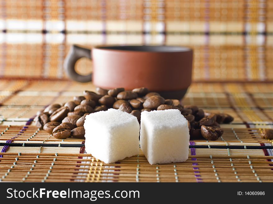 A cup of coffee, sugar cubes and coffee beans