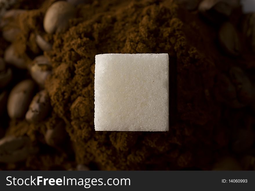 Sugar cube, lying on the ground sugar and surrounded by coffee beans. Sugar cube, lying on the ground sugar and surrounded by coffee beans