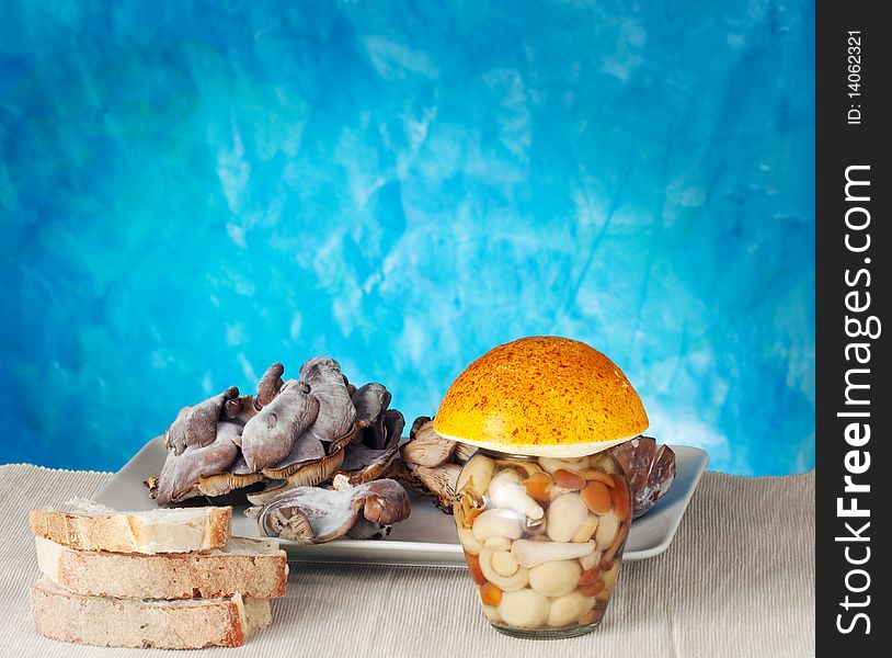 Bread near a jar of mushrooms on a blue background