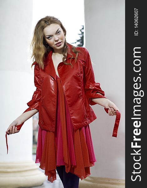 Fashion model in bright red Fall jacket near pillars. Fashion model in bright red Fall jacket near pillars