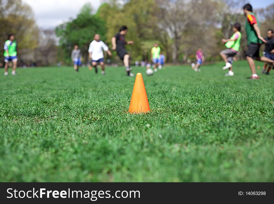 Orange safety cone in the grass in the soccer field. Shallow depth of field