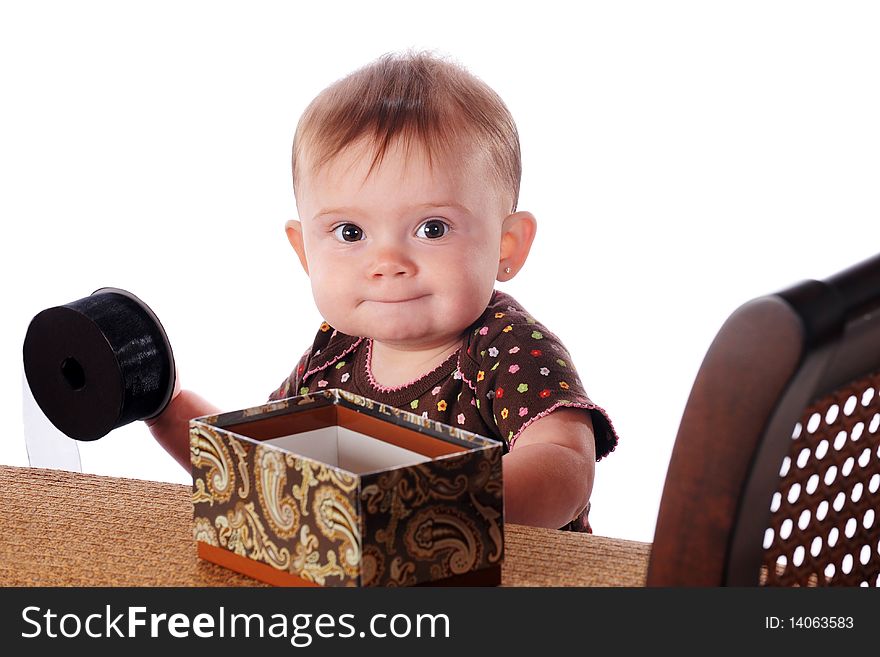 A new-standing baby playing with articles on the furniture that gives her balance.  Isolated on white. A new-standing baby playing with articles on the furniture that gives her balance.  Isolated on white.