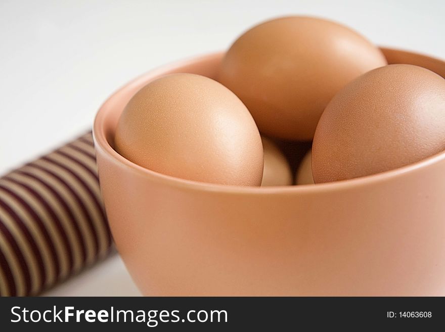 brown eggs in a big brown coffee cup with a stripped napkin beside it on white background. brown eggs in a big brown coffee cup with a stripped napkin beside it on white background