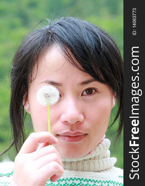 Portrait of Chinese girl covering her eye with dandelion. Portrait of Chinese girl covering her eye with dandelion