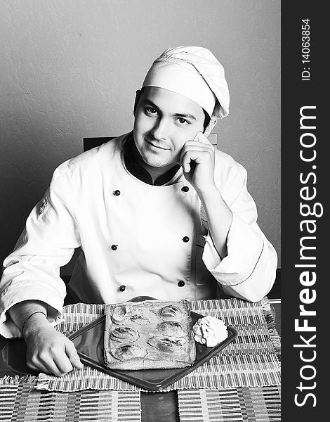 Handsome young chef in the professional manner in the living room with pirogovm from pears. Handsome young chef in the professional manner in the living room with pirogovm from pears