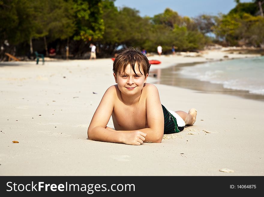 Boy is lying at the beach and enjoying the warmness of the water and looking self confident and happy. Boy is lying at the beach and enjoying the warmness of the water and looking self confident and happy