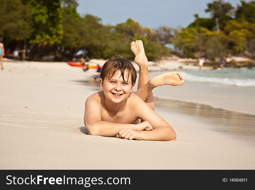 Boy is lying at the beach and enjoying the warmness of the water and looking self confident and happy. Boy is lying at the beach and enjoying the warmness of the water and looking self confident and happy