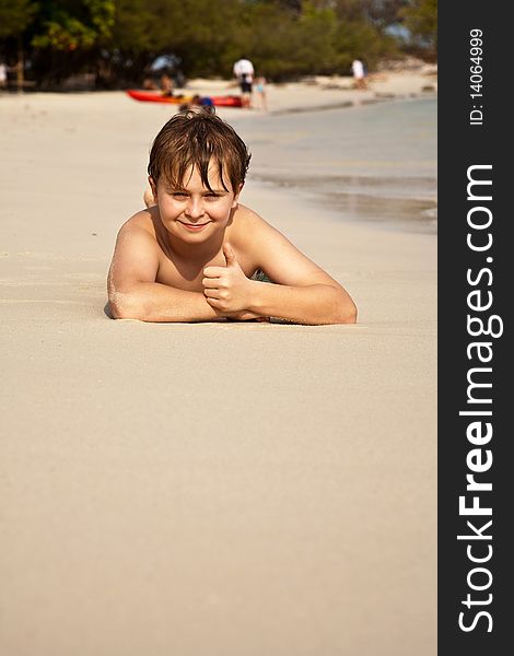 Boy is lying at the beach and enjoying the warmness of the water and looking self confident and happy. Boy is lying at the beach and enjoying the warmness of the water and looking self confident and happy