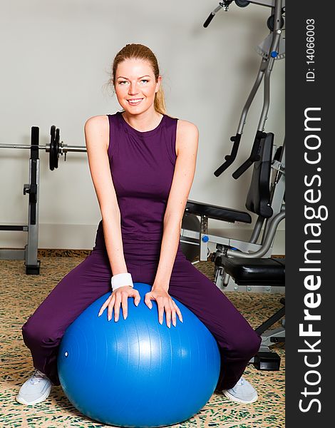 Portrait of young, attractive women sitting on exercise ball in a health club. Verticall shot. Portrait of young, attractive women sitting on exercise ball in a health club. Verticall shot.