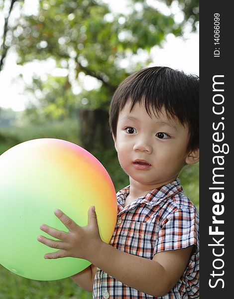An Asian boy playing with a colorful ball at a public park. An Asian boy playing with a colorful ball at a public park