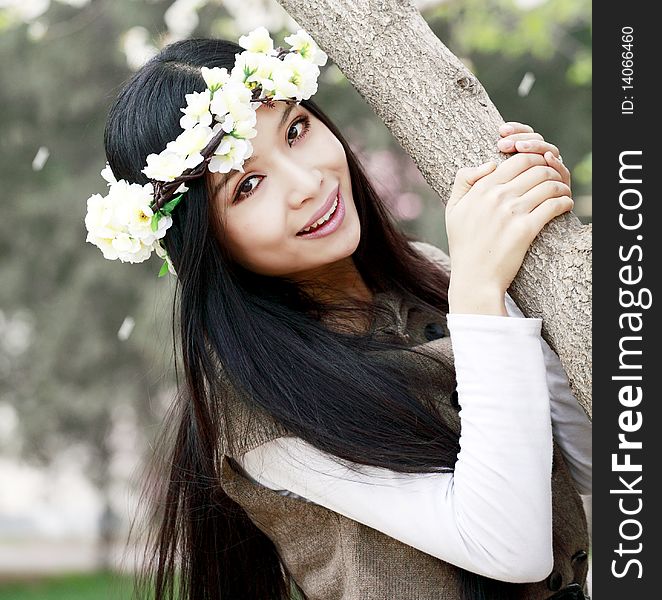 Smiling Asian girl with garlands under cherry tree. Smiling Asian girl with garlands under cherry tree.