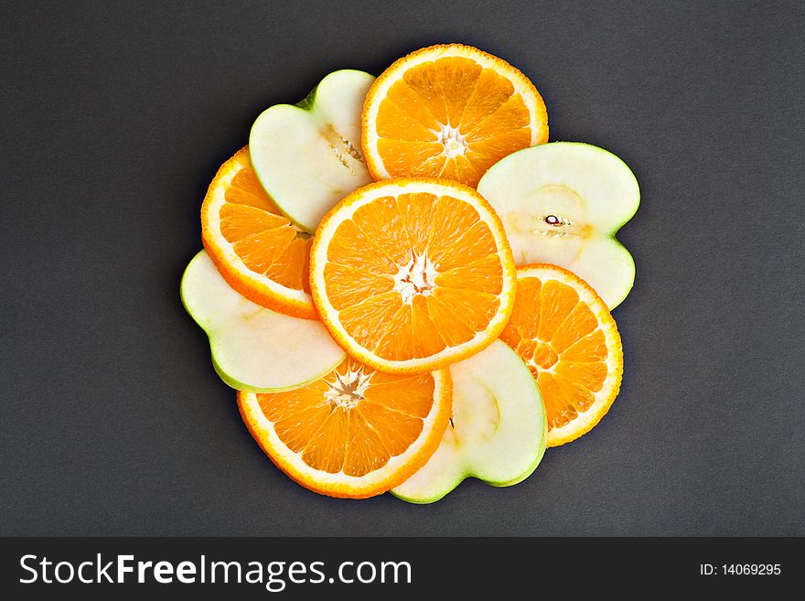 Orange and apple slices against a dark background