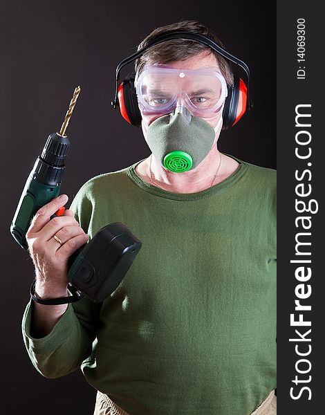 Man with a drill in a mask and a respirator. Man with a drill in a mask and a respirator
