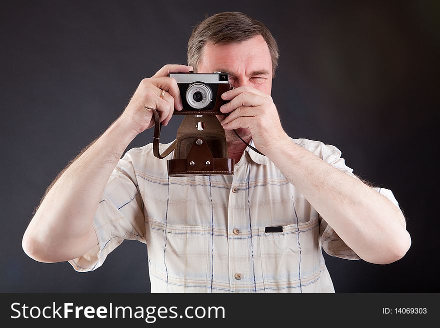 Man with the ancient camera against a dark background. Man with the ancient camera against a dark background