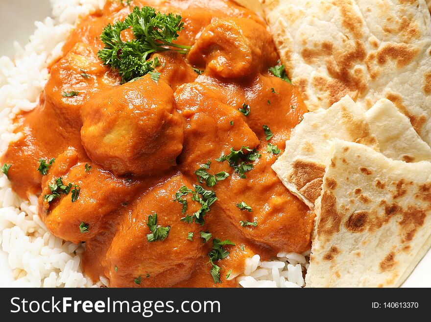 Delicious butter chicken with rice and naan as background