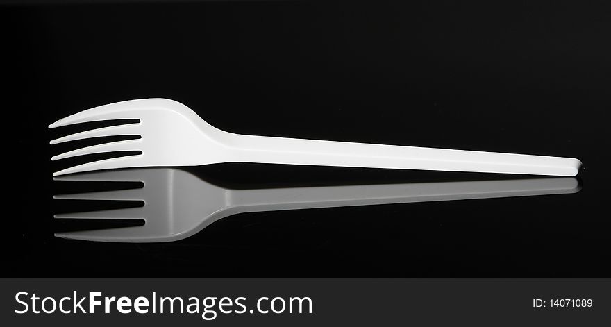 White plastic fork on a black reflecting surface