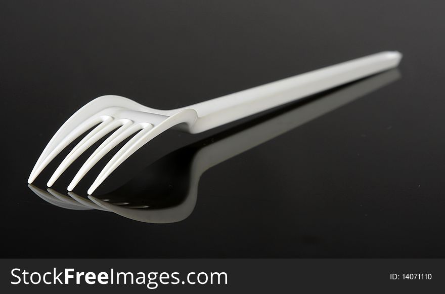 White plastic fork on a black reflecting surface