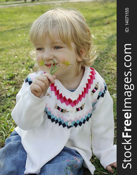 The little girl sniffing the flowers on the walk. The little girl sniffing the flowers on the walk