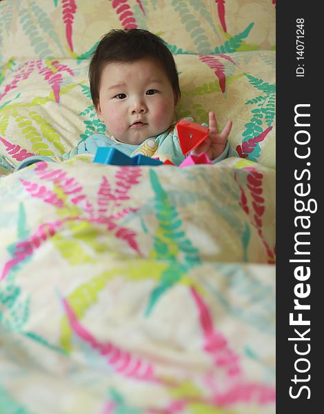 Lovely Chinese baby playing toy in the bed. Lovely Chinese baby playing toy in the bed